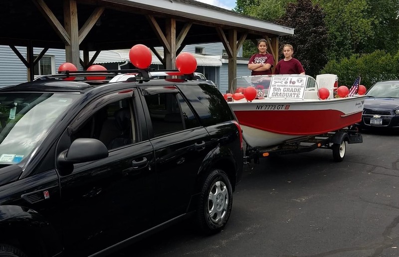 Students in decorated boat being pulled by vehicle
